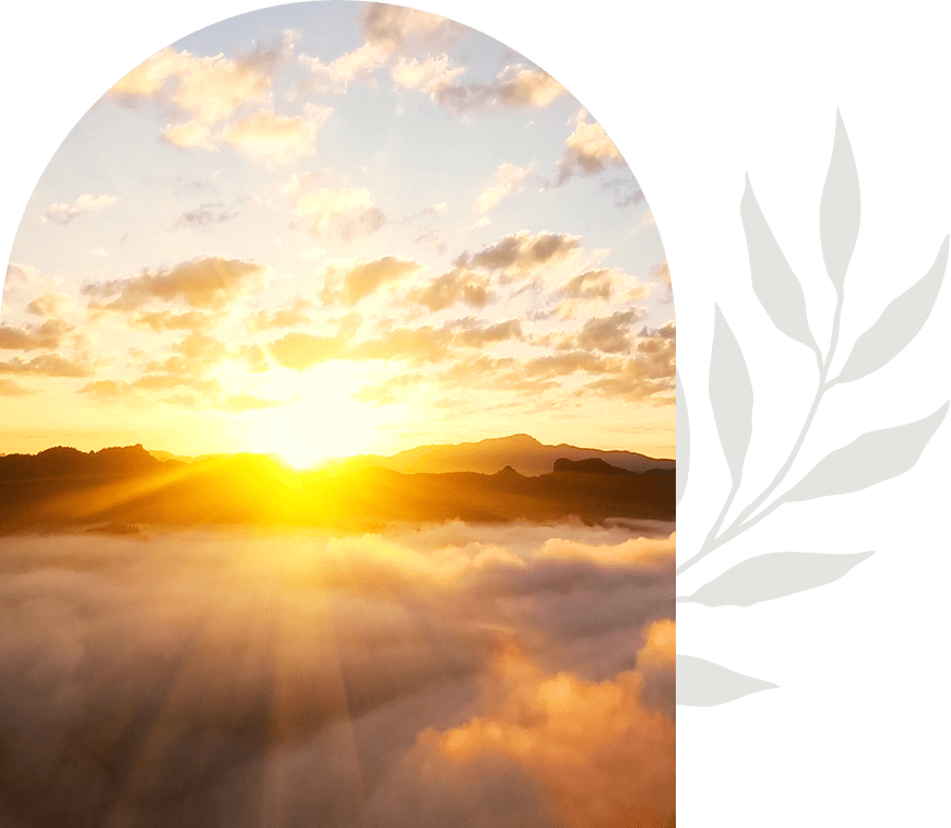 Sunrise viewed through an arched window with fog and hills.